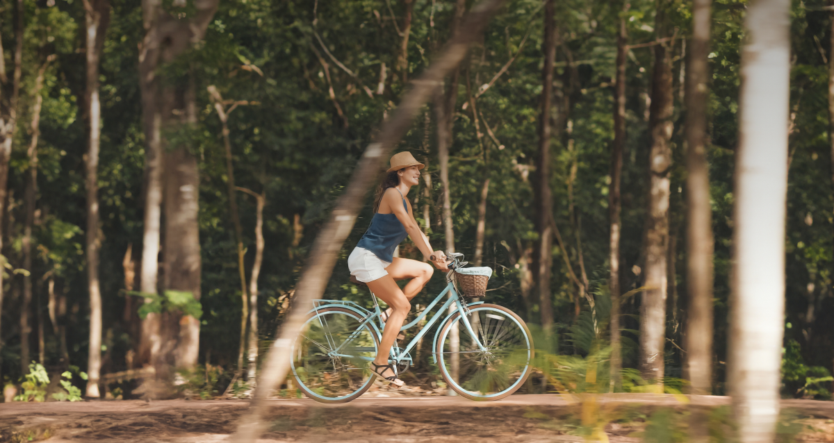 Mamá recorriendo en bicicleta Ciudad Mayakoba rodeada de naturaleza tropical y cerca del Caribe